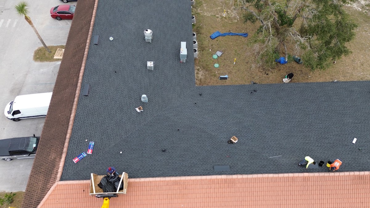 Roofers working on a large dark shingle roof.